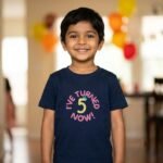 Smiling boy wearing a navy blue kids tshirt with I've Turned 5 Now! birthday embroidery