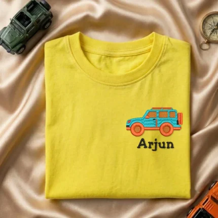 Folded yellow kids t-shirt with small SUV embroidery and custom name Arjun on the left chest